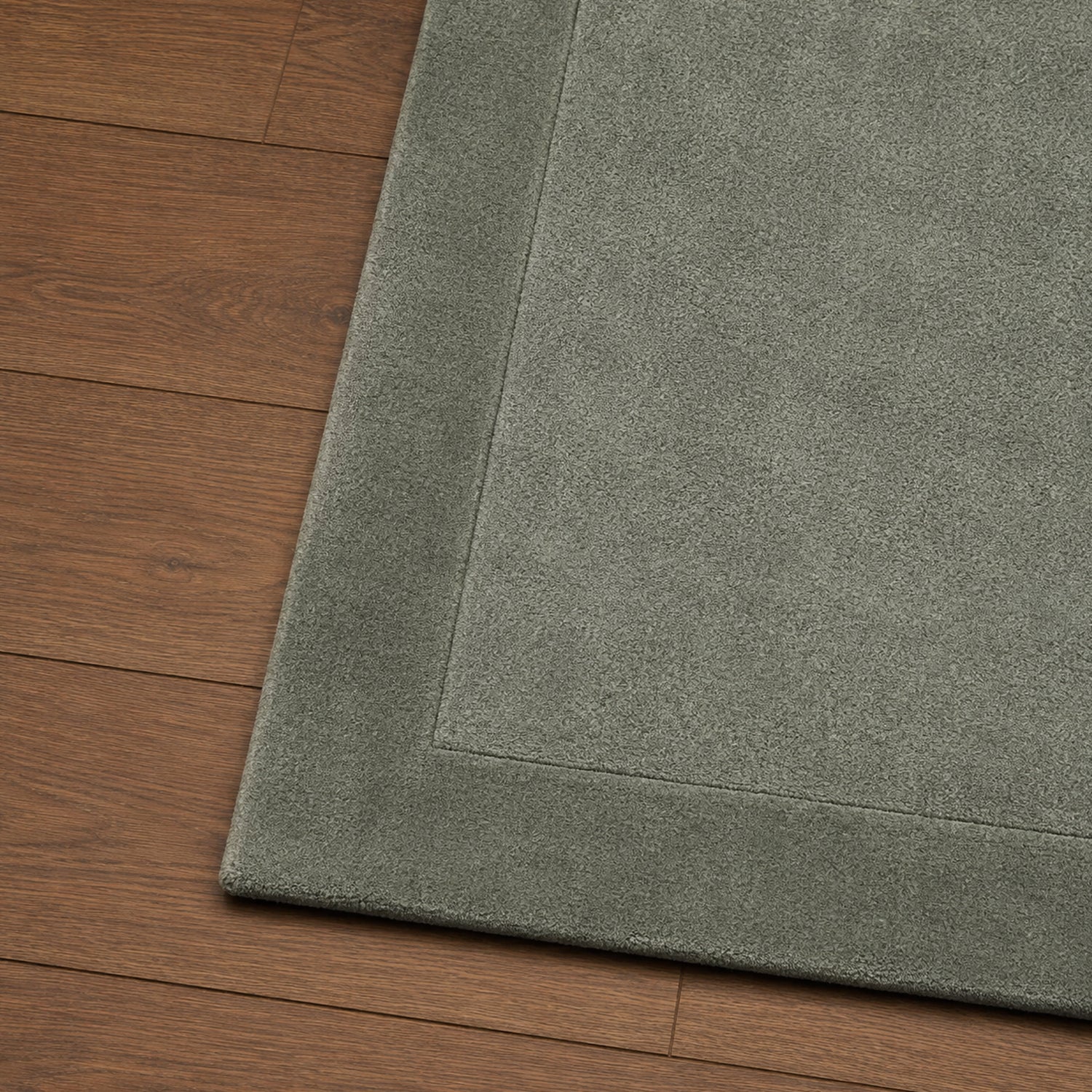 Close-up of the Gracious Living Sabrina Sage Area Rug showing the soft textured pile, stitched border detail and rounded corner on warm timber flooring.