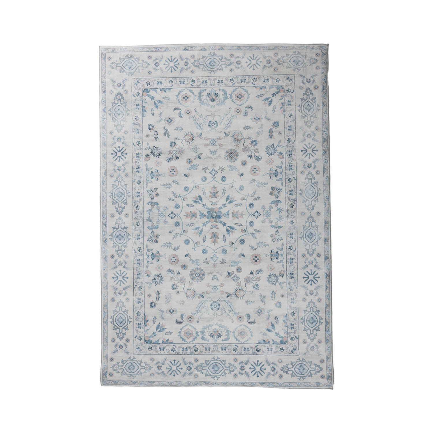 A rectangular area rug with a traditional floral pattern in shades of blue, gray, and beige on a light off-white background, shown flat against a white studio backdrop.