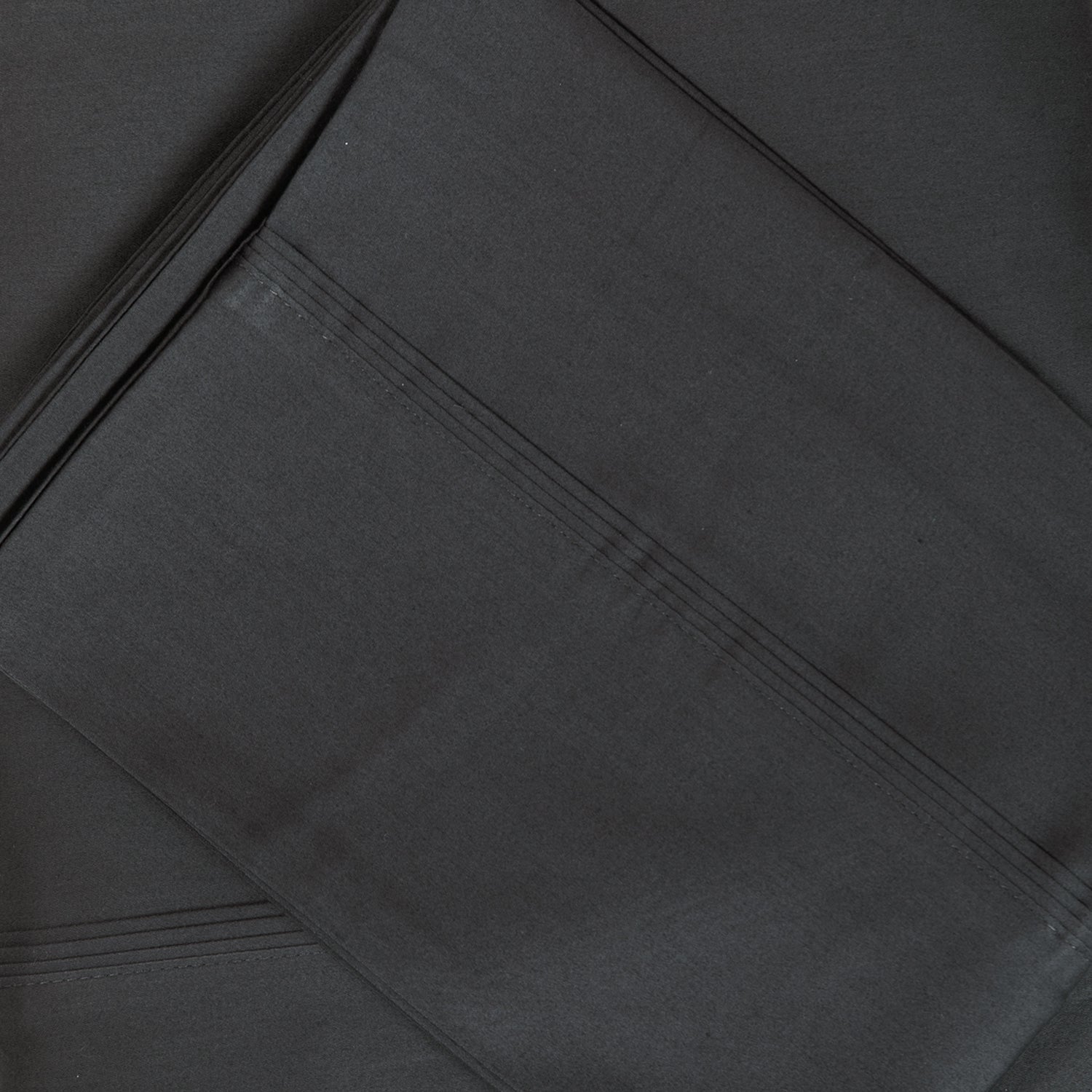 A close-up of crisp graphite sateen bed sheets showcases its smooth, lustrous finish and refined stitched cuff detailing for a timeless, luxurious look.