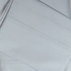 A close-up of crisp ice blue sateen bed sheets showcases its smooth, lustrous finish and refined stitched cuff detailing for a timeless, luxurious look.