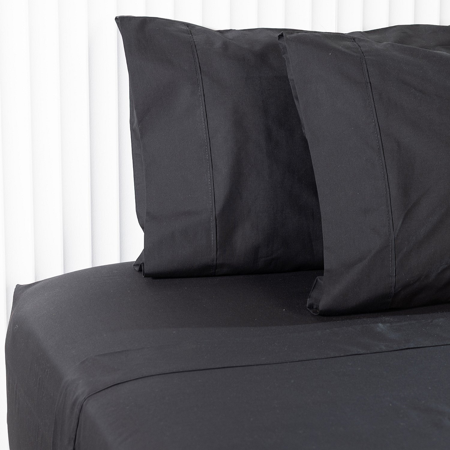 Black bed flat sheets and pillows on a white background