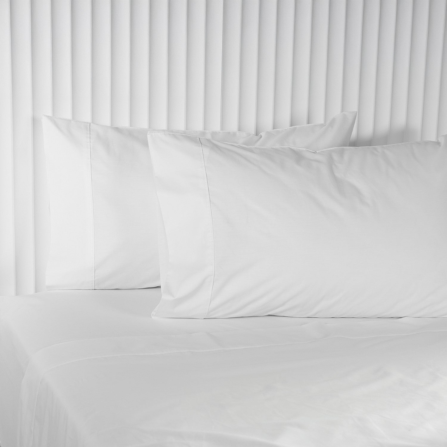 White pillows on a bed with a white headboard