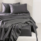 A luxurious charcoal sheet set is beautifully styled on a contemporary upholstered bed, showcasing its smooth, crisp finish and timeless elegance.