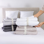 A collection of premium sheet sets in timeless neutral tones is neatly organised with reusable branded storage bands, showcasing elegant storage and effortless linen organisation.