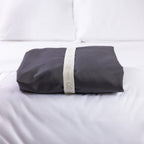 A neatly folded sheet set is secured with a reusable branded storage band, showcasing elegant presentation and effortless linen organisation.