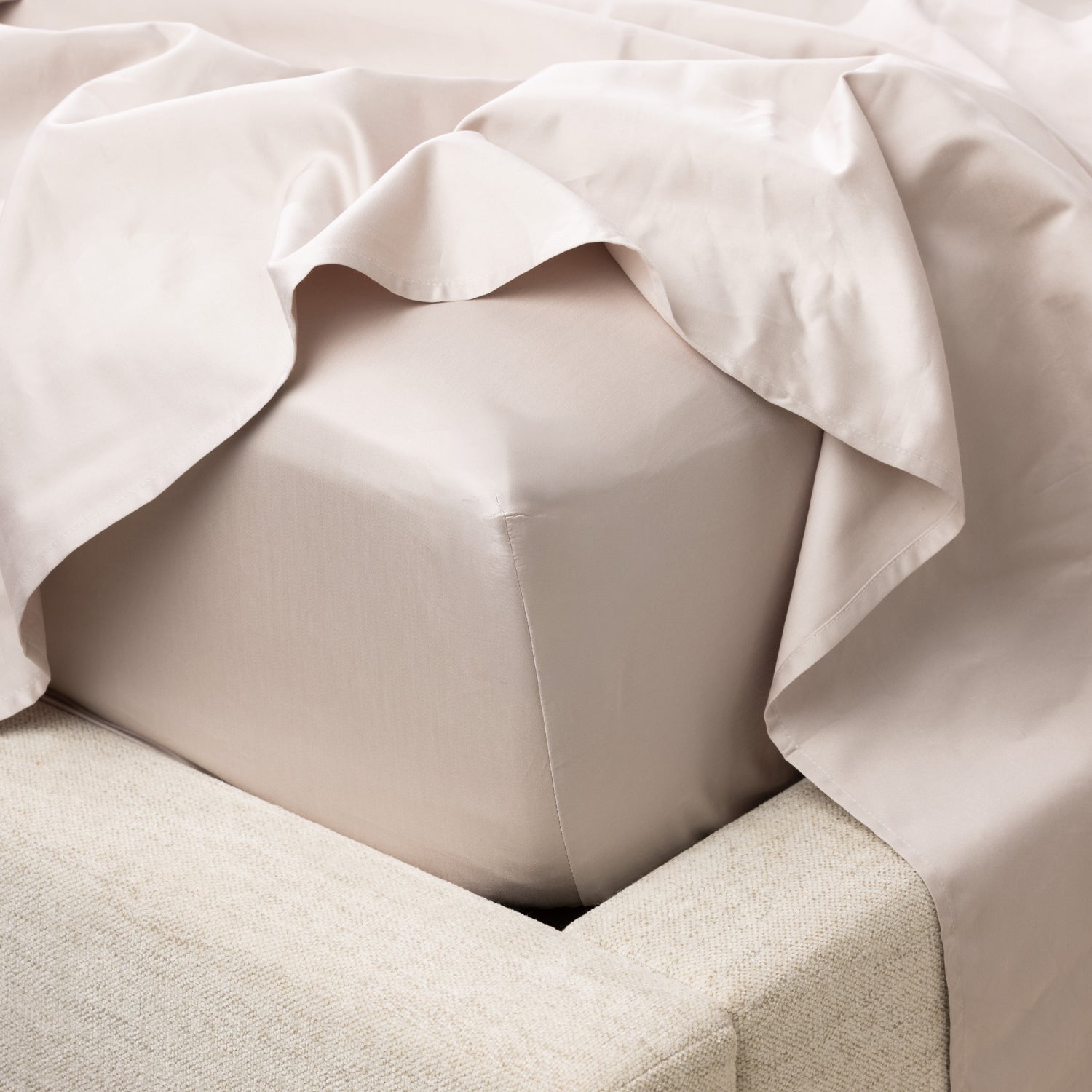 A close-up of a fitted sheet wrapped smoothly around the mattress highlights its crisp finish, tailored fit and luxurious sateen-like appearance.