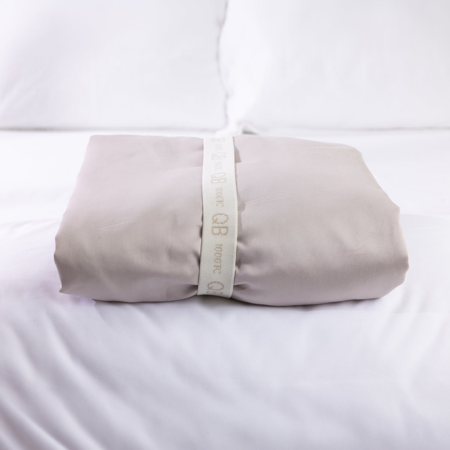 A neatly folded sheet is secured with a reusable branded storage band, showcasing elegant presentation and effortless linen organisation.