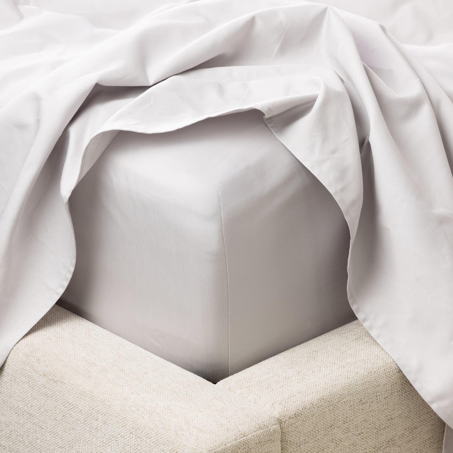 A close-up of a fitted sheet wrapped smoothly around the mattress highlights its crisp finish, tailored fit and luxurious sateen-like appearance.