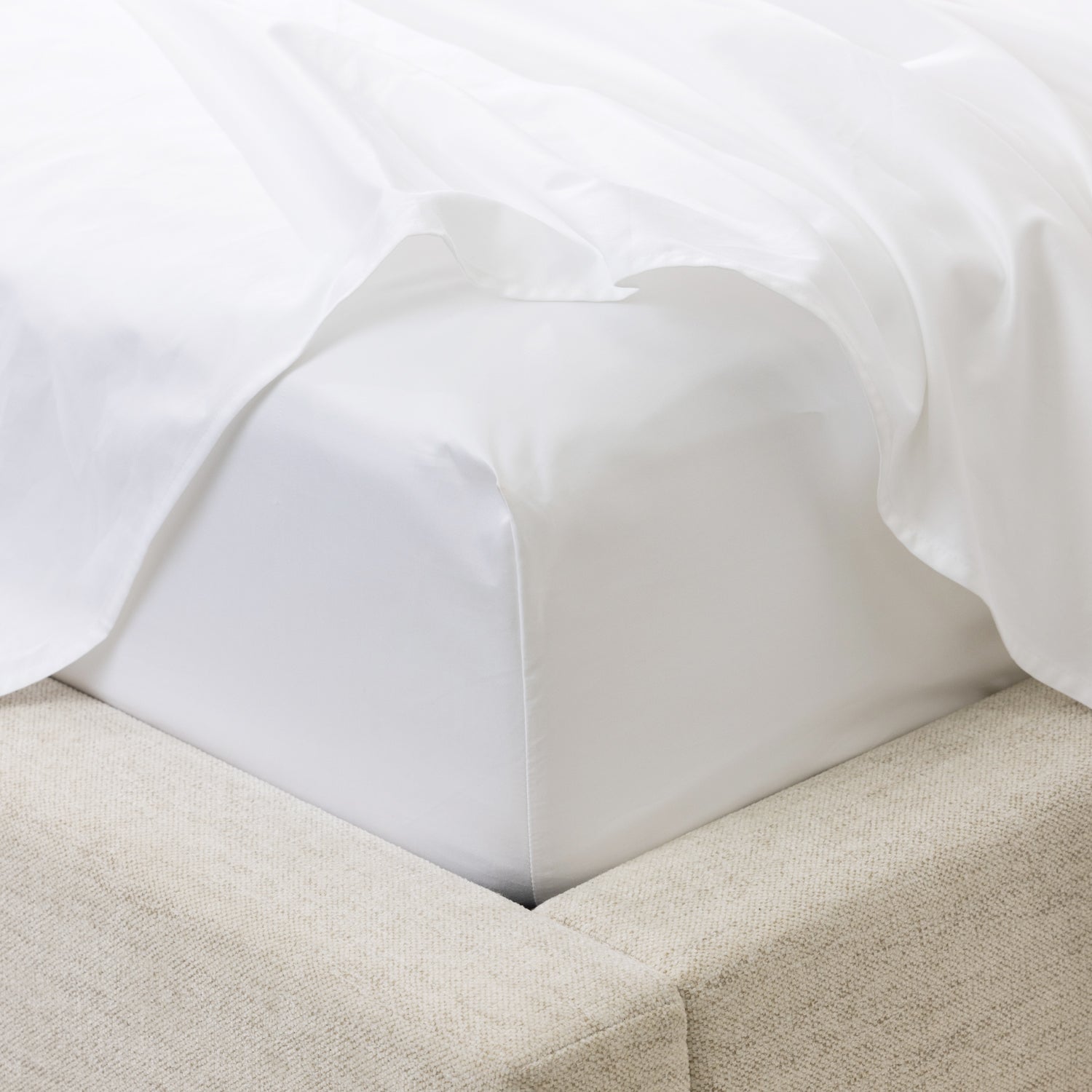 A close-up of a fitted sheet wrapped smoothly around the mattress highlights its crisp finish, tailored fit and luxurious sateen-like appearance.