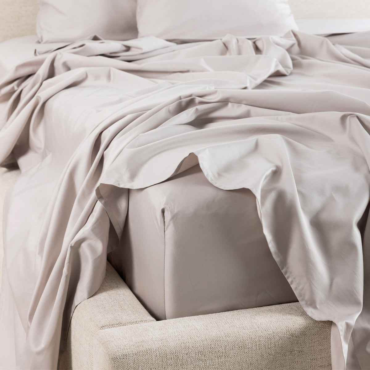 A close-up of the Gracious Living Avery Sheet Set in Silver, featuring smooth cotton sateen sheets draped across a bed with matching pillowcases and a fitted sheet.
