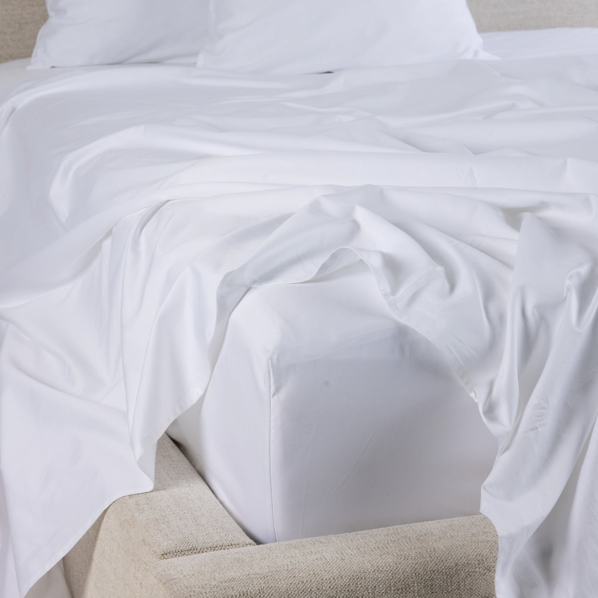 A close-up of the Gracious Living Avery Sheet Set in White, featuring smooth white cotton sateen sheets draped across a bed with matching pillowcases and a fitted sheet.