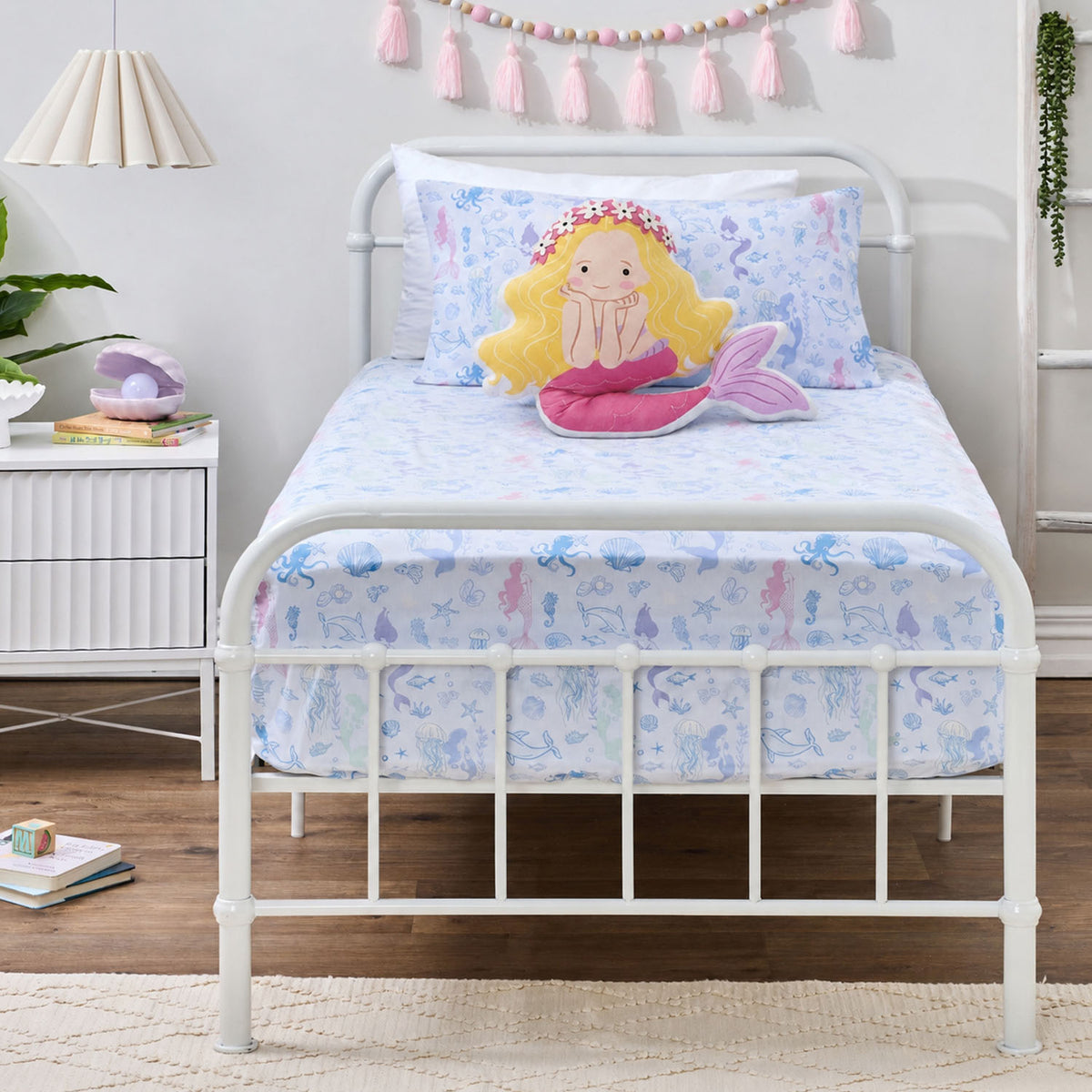 Mermaid Dreams fitted sheet set styled on a white metal bed with matching printed pillowcase and a decorative mermaid cushion.