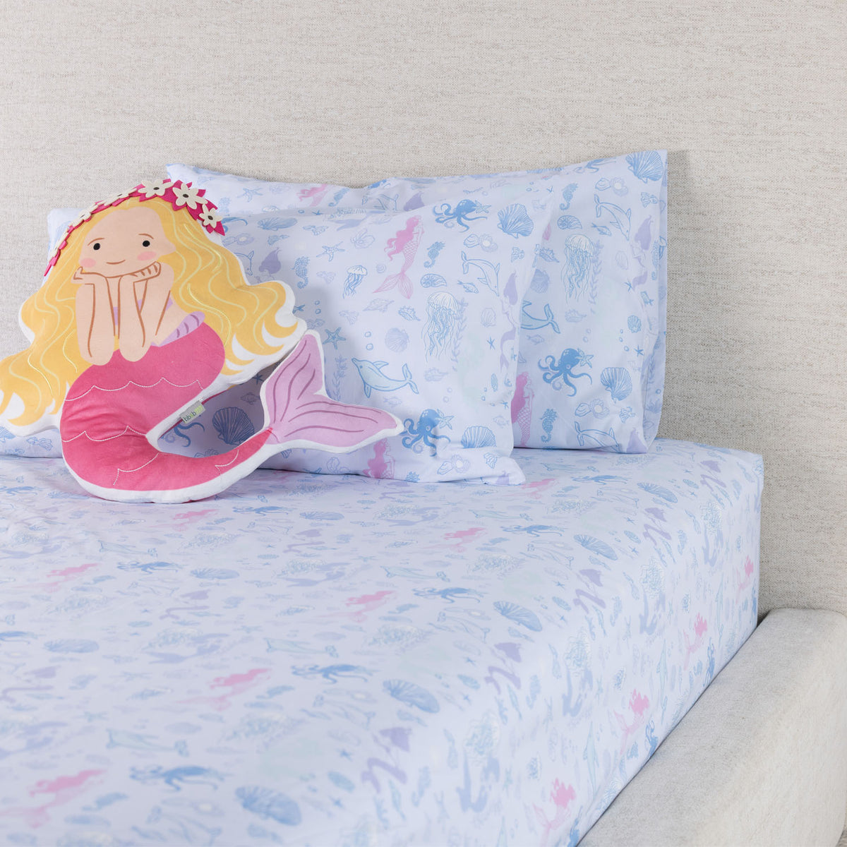 Mermaid Dreams fitted sheet set styled on a bed with matching printed pillowcases and a decorative mermaid cushion.