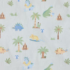 Close-up of the Dino Beach Party fabric print featuring colourful dinosaurs, palm trees, sandcastles, beach balls and tropical leaves on a pale blue background.