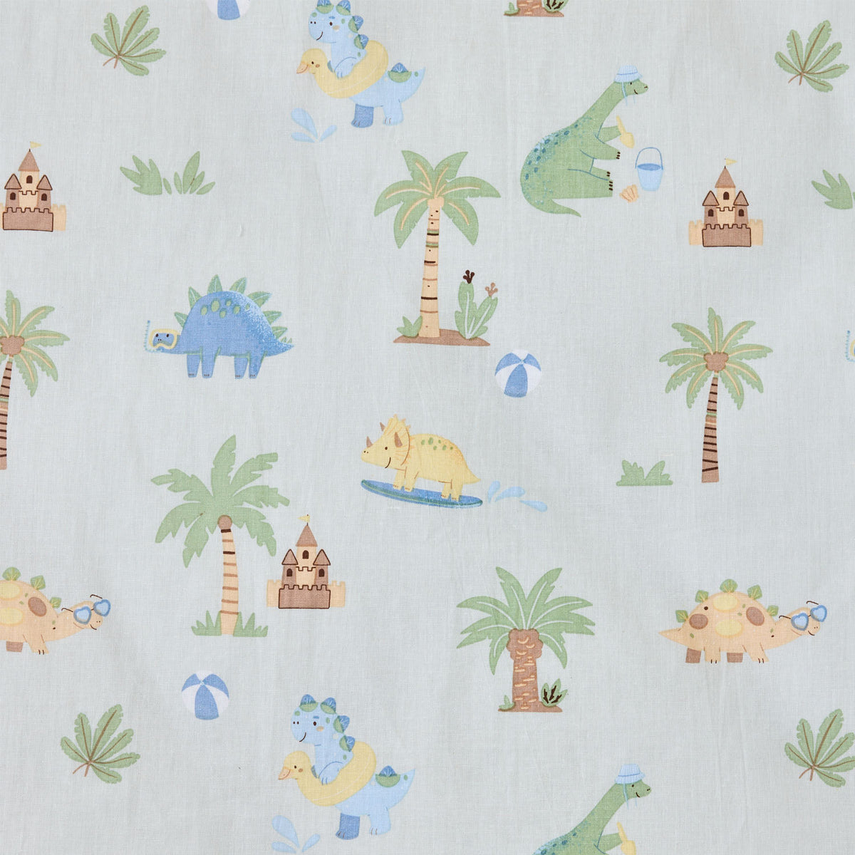 Close-up of the Dino Beach Party fabric print featuring colourful dinosaurs, palm trees, sandcastles, beach balls and tropical leaves on a pale blue background.