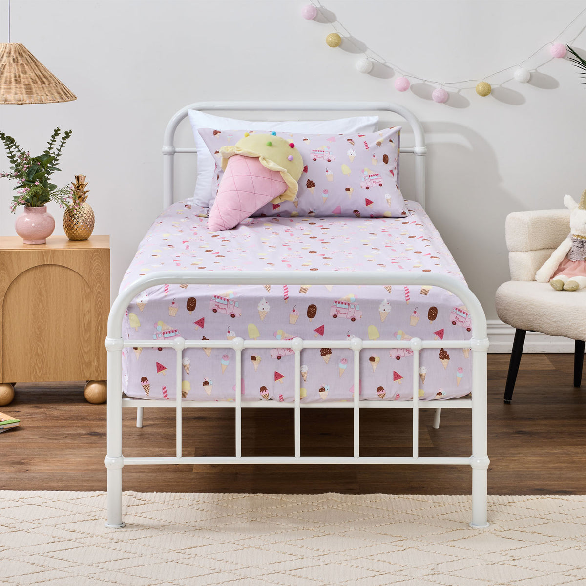 Ice Cream Shop fitted sheet set styled on a white metal bed with matching printed pillowcase and a playful ice cream cone cushion.