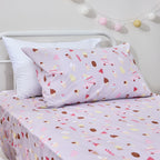 Close-up of the Ice Cream Shop fitted sheet and pillowcase showing colourful ice creams, popsicles, cones and pink ice cream trucks on a lilac background.