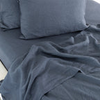 Midnight blue linen bedding is beautifully styled with softly crumpled sheets and plush pillows, showcasing its natural texture and relaxed, lived-in elegance.