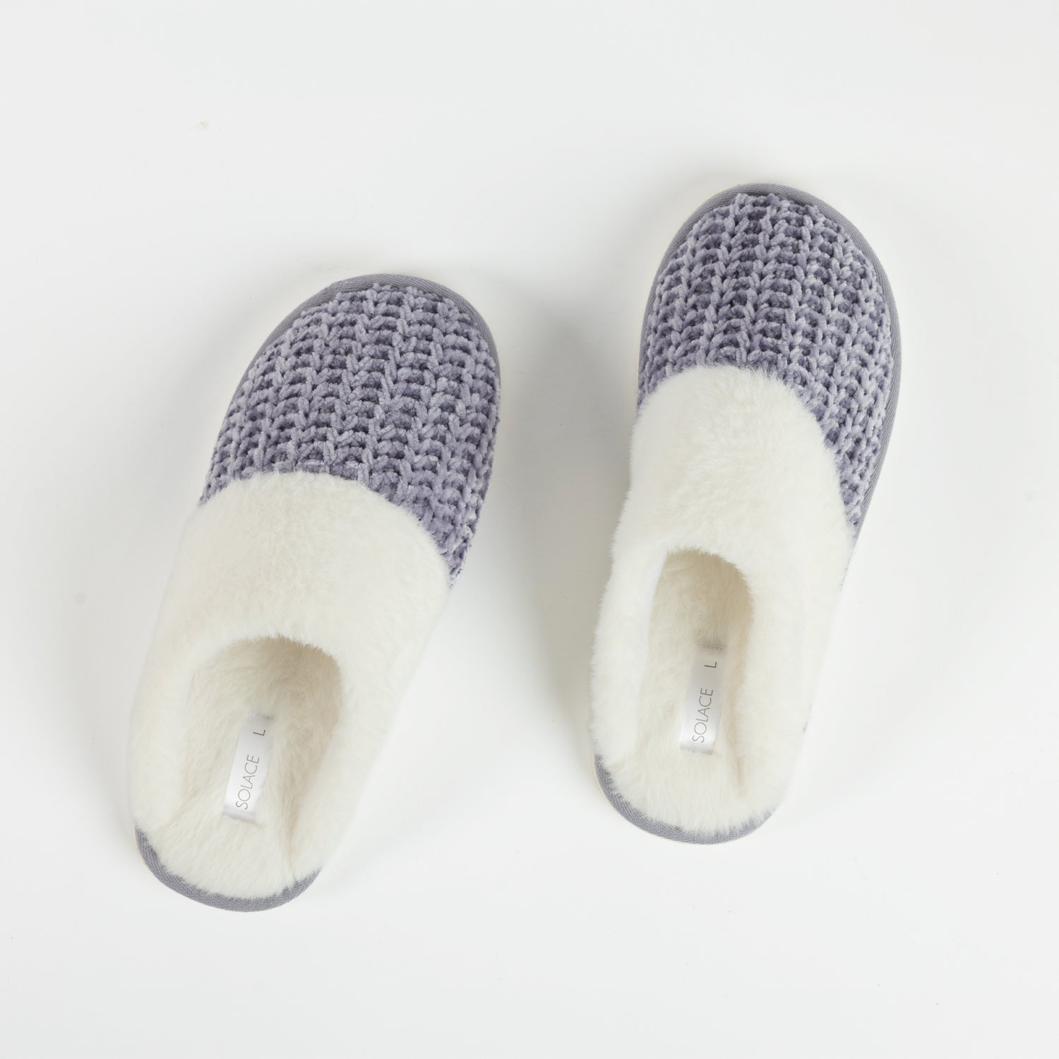 A pair of lilac chenille slippers with plush white faux fur lining are displayed on a clean white background, highlighting their soft texture and cosy design.