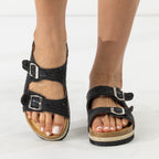 A pair of women's black woven platform sandals with double adjustable buckles, shown on a model's feet against a white studio background.