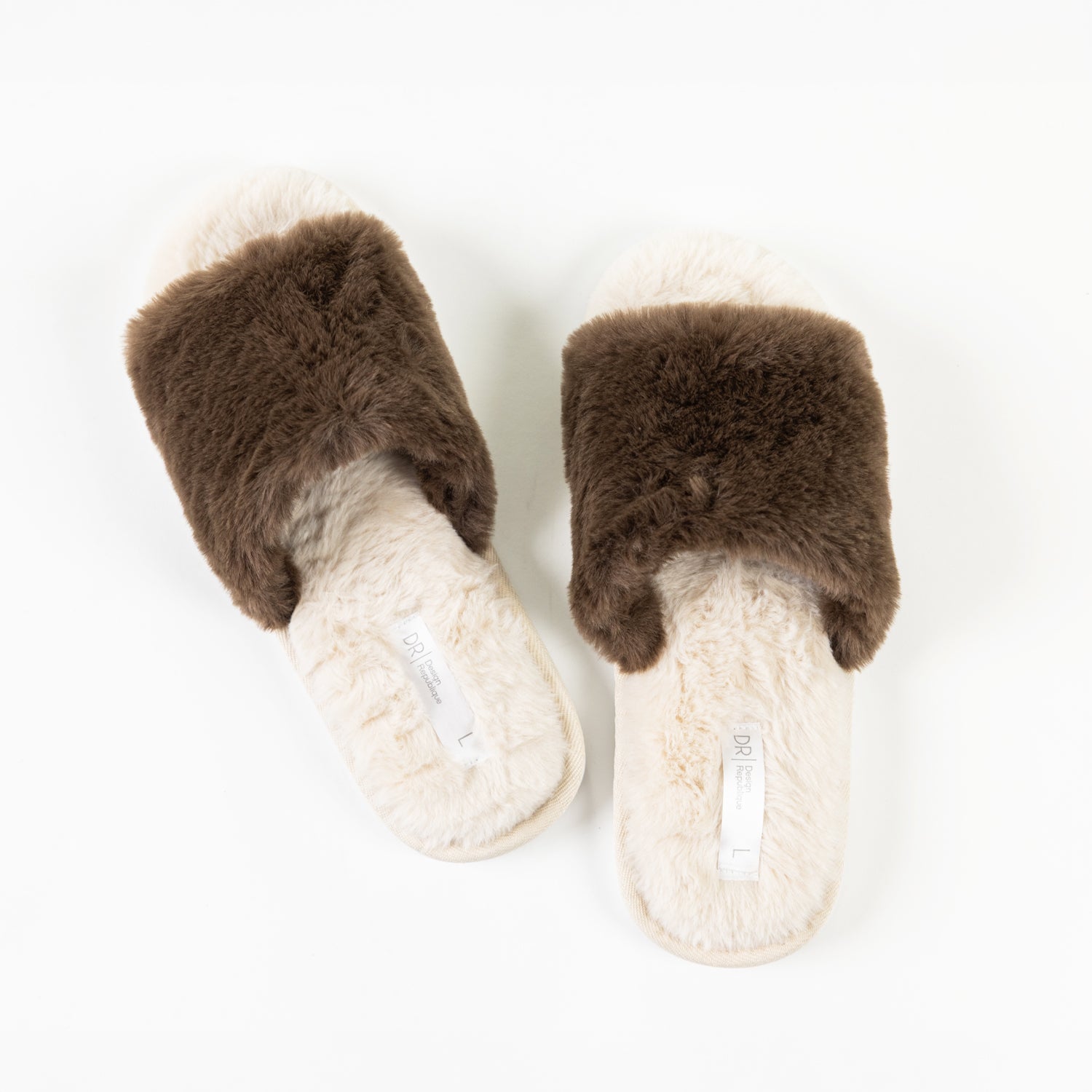 A pair of fluffy chocolate faux fur slippers with soft beige footbeds is displayed from above, showcasing their plush texture and cosy open-toe design.