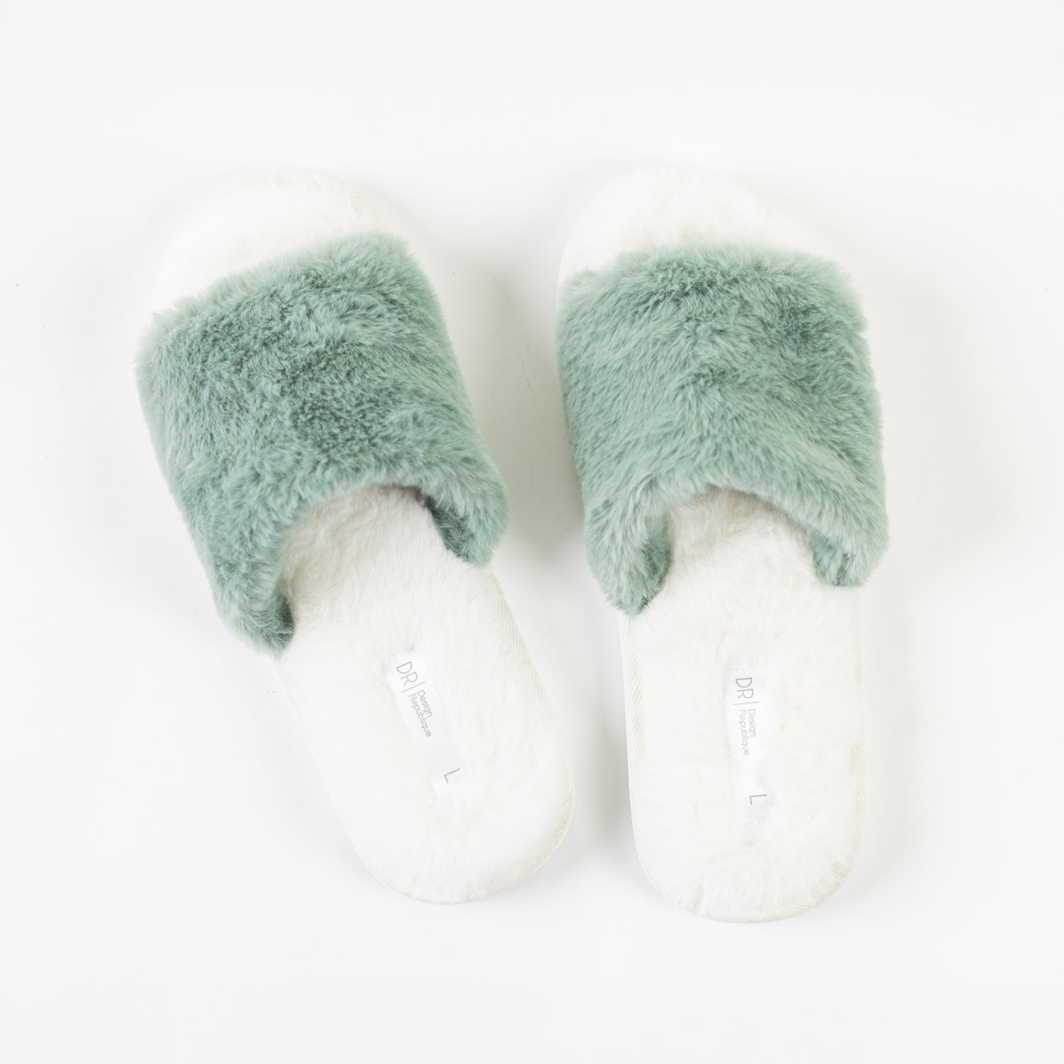 A pair of fluffy sage green faux fur slippers with soft white footbeds is displayed from above, showcasing their plush texture and cosy open-toe design.