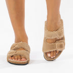 Tan fuzzy sandals worn on a white background