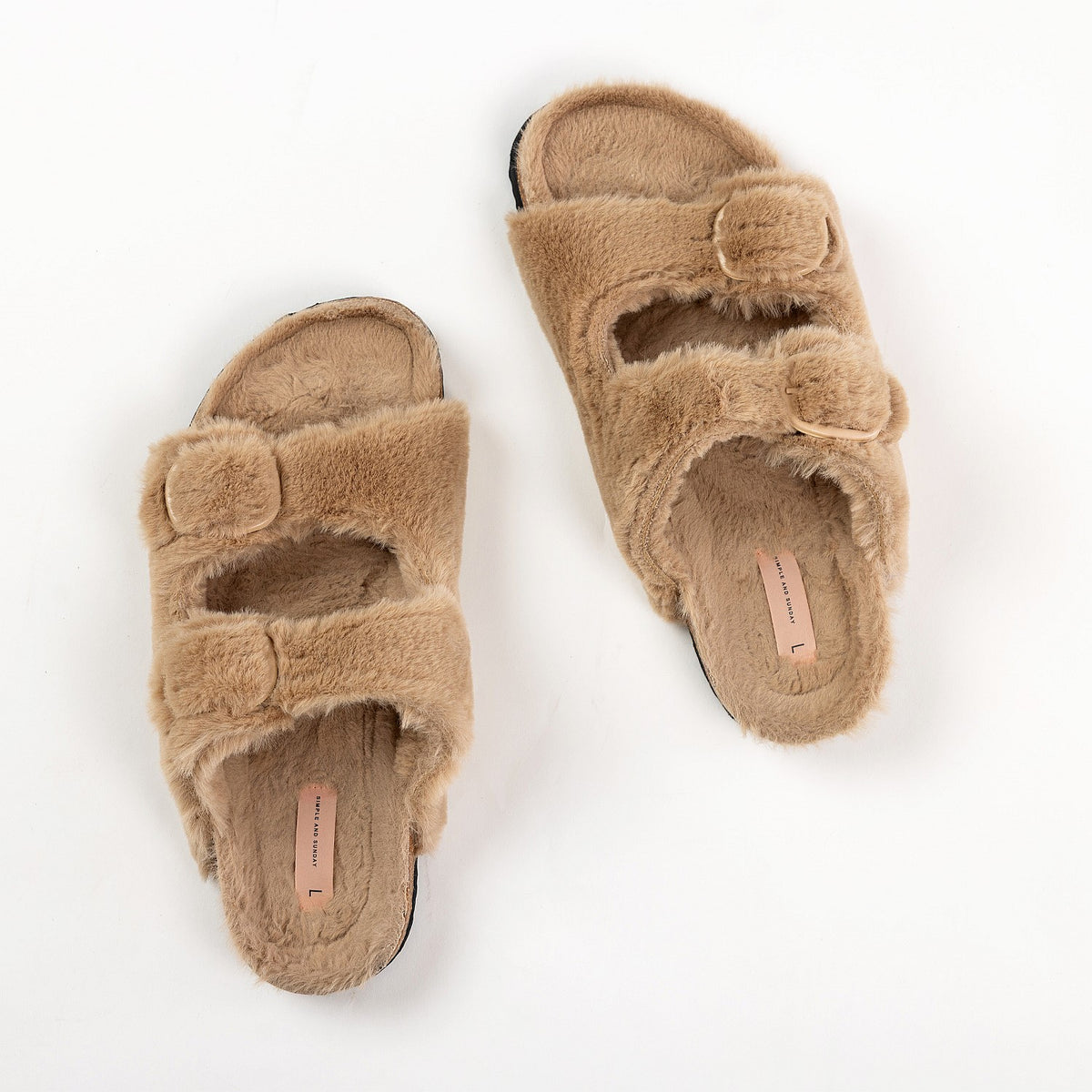 Pair of beige fuzzy slippers on a white background