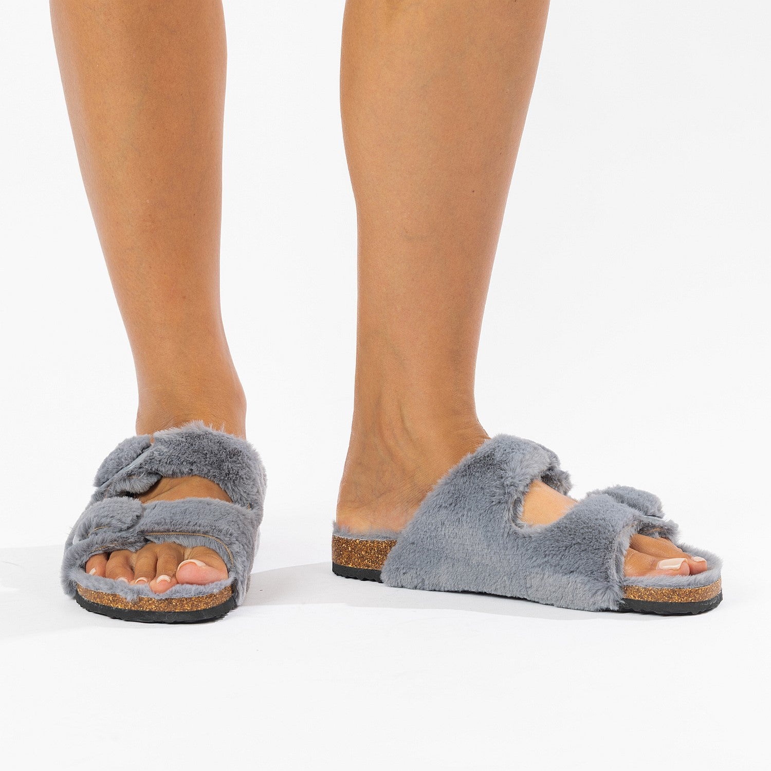 Gray fuzzy slippers worn by a person on a white background