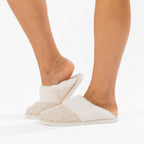 White fluffy slippers worn by a person on a white background