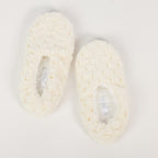 Pair of white crocheted slippers on a light gray background