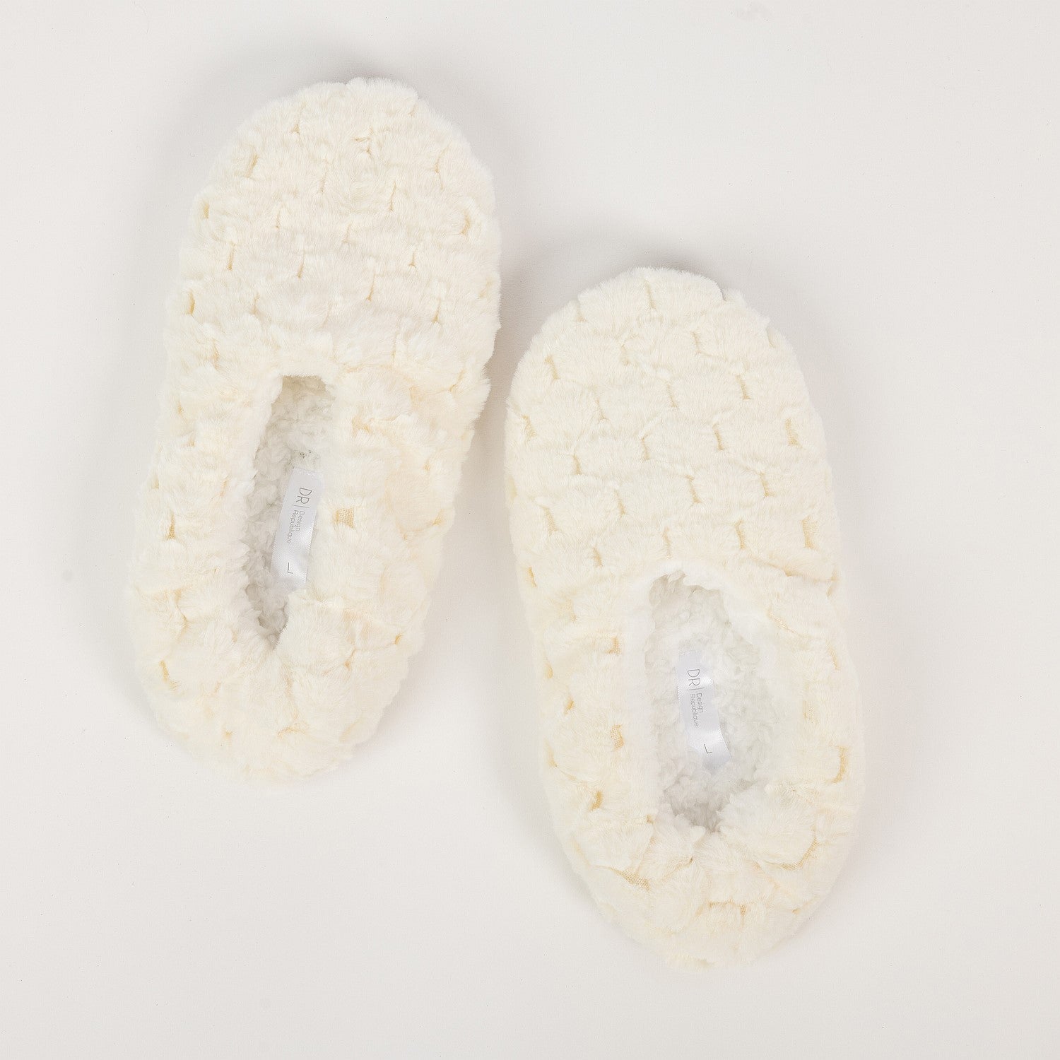 Pair of white crocheted slippers on a light gray background