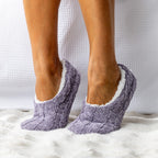Purple cable knit socks with white lining worn by a person on a white textured surface.