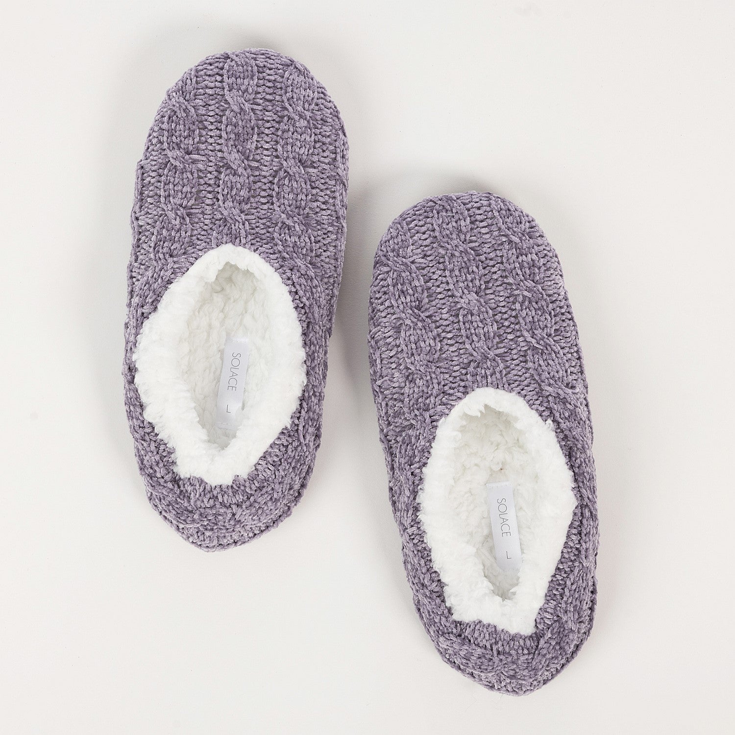Pair of purple fuzzy socks with white lining on a light gray background