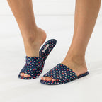 Navy floral open-toe slippers shown being worn while stepping into one slipper.