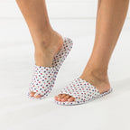 Ivory floral open-toe slippers shown being worn while stepping into one slipper.