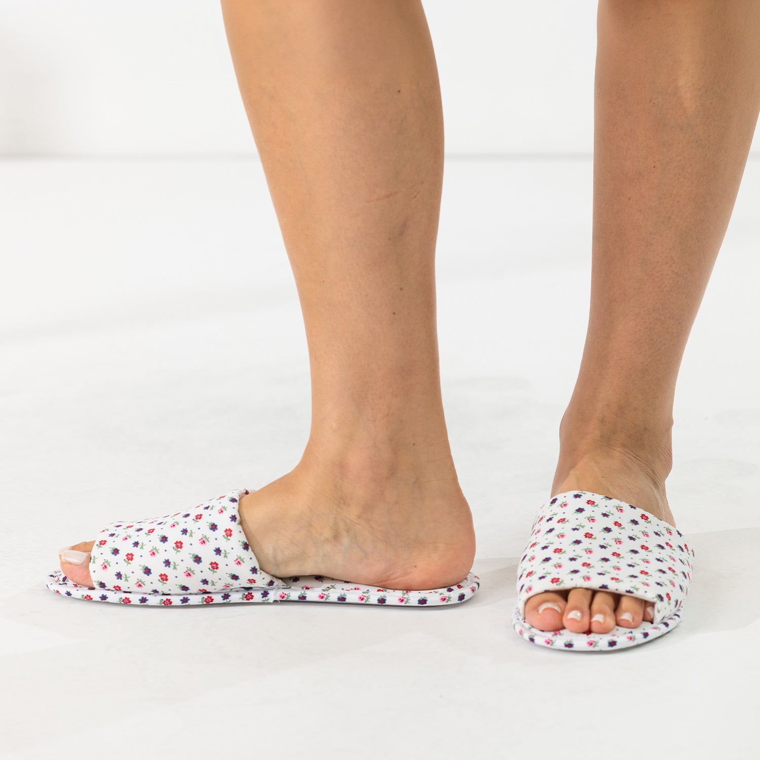 Ivory floral open-toe slippers shown being worn from the front and side.
