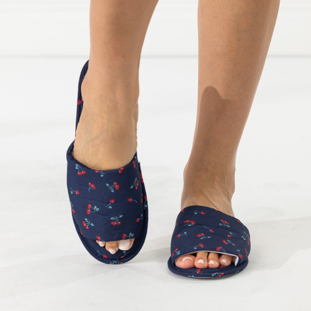 Solace Gracie Quilted Slippers Navy with a red cherry print, shown worn from the front.