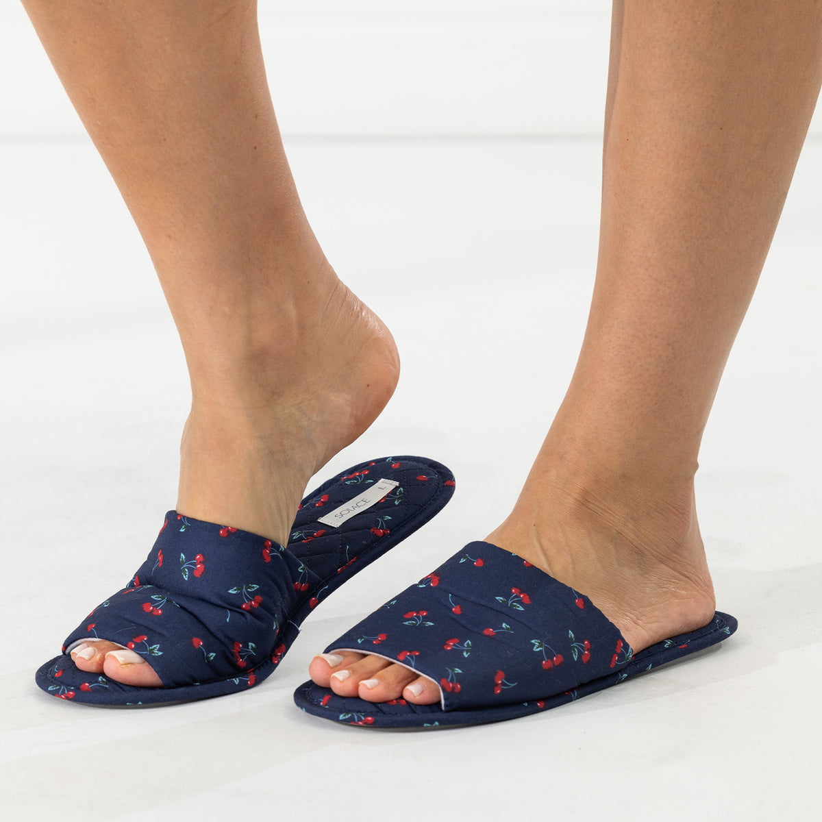 Solace Gracie Quilted Slippers Navy with a red cherry print, shown worn from an angled view.