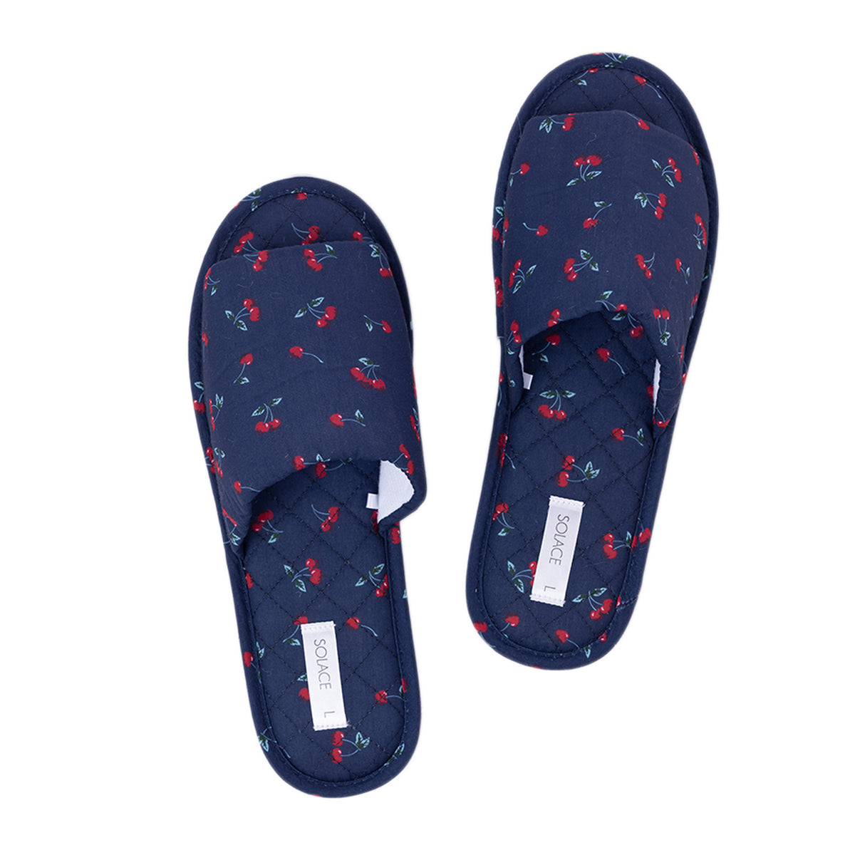 Pair of Solace Gracie Quilted Slippers Navy featuring a red cherry print and quilted footbeds.