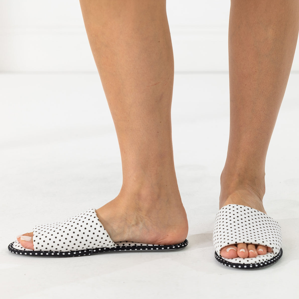 Solace Gracie Quilted Slippers White featuring a black polka dot print, shown worn from the side and front.