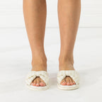 Front view of ivory open-toe slippers with soft padded crossover straps and bow-inspired detailing.