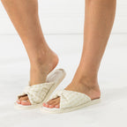 Angled side view of the ivory bow slippers showing the padded crossover straps and low-profile sole.