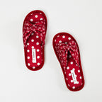 Top view of a pair of raspberry red open-toe slippers featuring cushioned footbeds with white polka dots, decorative bow-style straps with a white bandana print, and coordinating red trim on a white background.