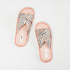 Top view of a pair of pink open-toe slippers featuring cushioned footbeds, crossover straps with a blue and cream paisley bandana print, and coordinating pink trim on a white background.