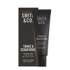Smith & Co. Tabac & Cedarwood Hand & Nail Pomade 80ml in a black tube displayed alongside its matching black packaging against a white background.