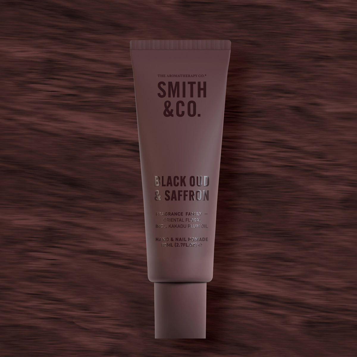 Smith & Co. Black Oud & Saffron Hand & Nail Pomade 80ml in a burgundy tube against a dark burgundy woodgrain background.