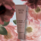 Smith & Co. Blush Rose & Blackberry Hand & Nail Pomade 80ml in a dusty pink tube surrounded by soft pink flowers.