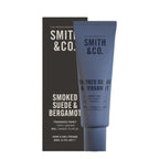 Smith & Co. Smoked Suede & Bergamot Hand & Nail Pomade 80ml displayed alongside its black packaging against a white background.