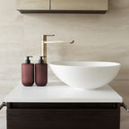 Two Smith & Co. deep burgundy pump bottles displayed beside a white vessel basin and brushed brass tap on a modern bathroom countertop.